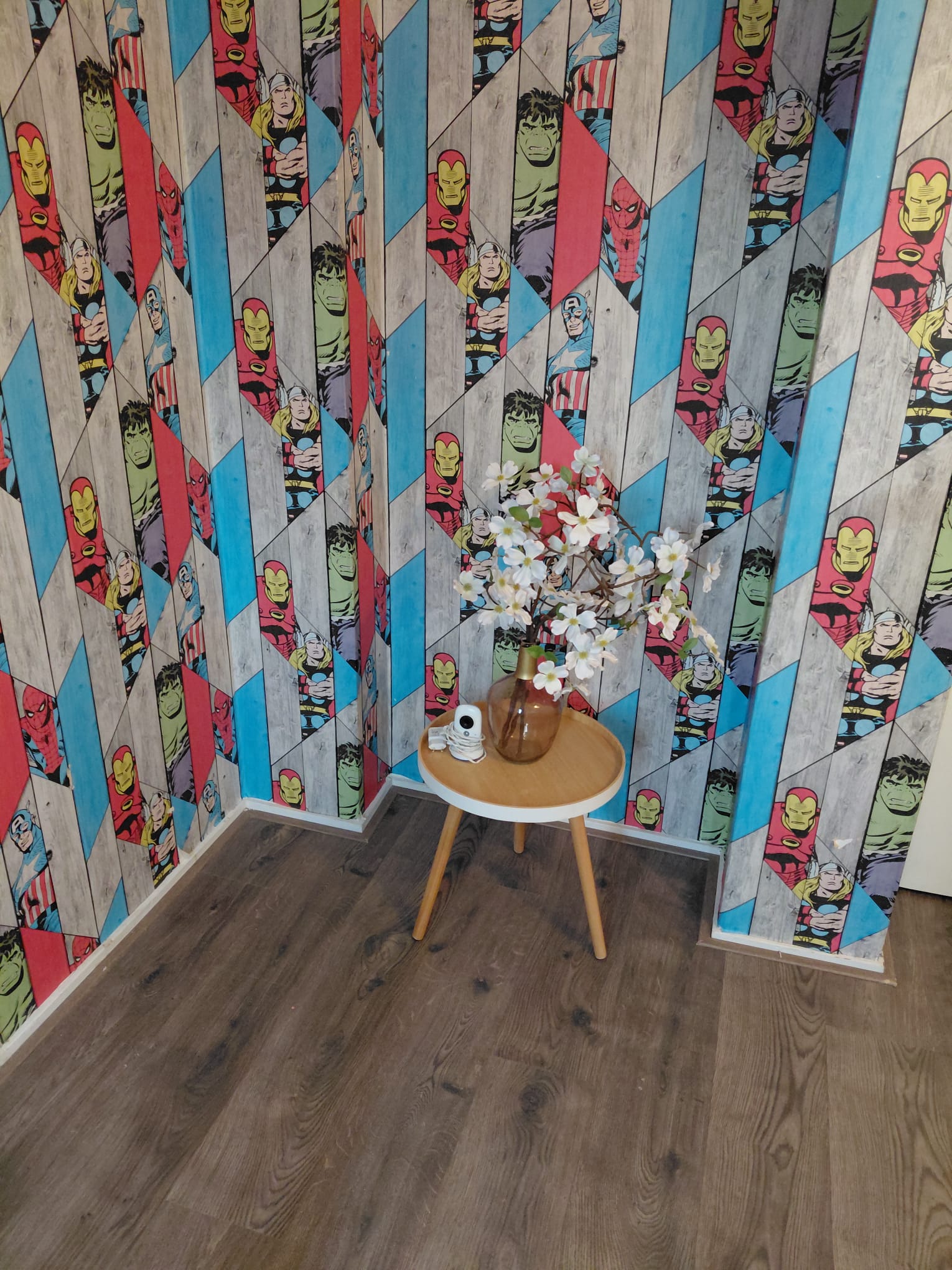 Kleurrijke superheldenwand met een klein tafeltje en bloemen
