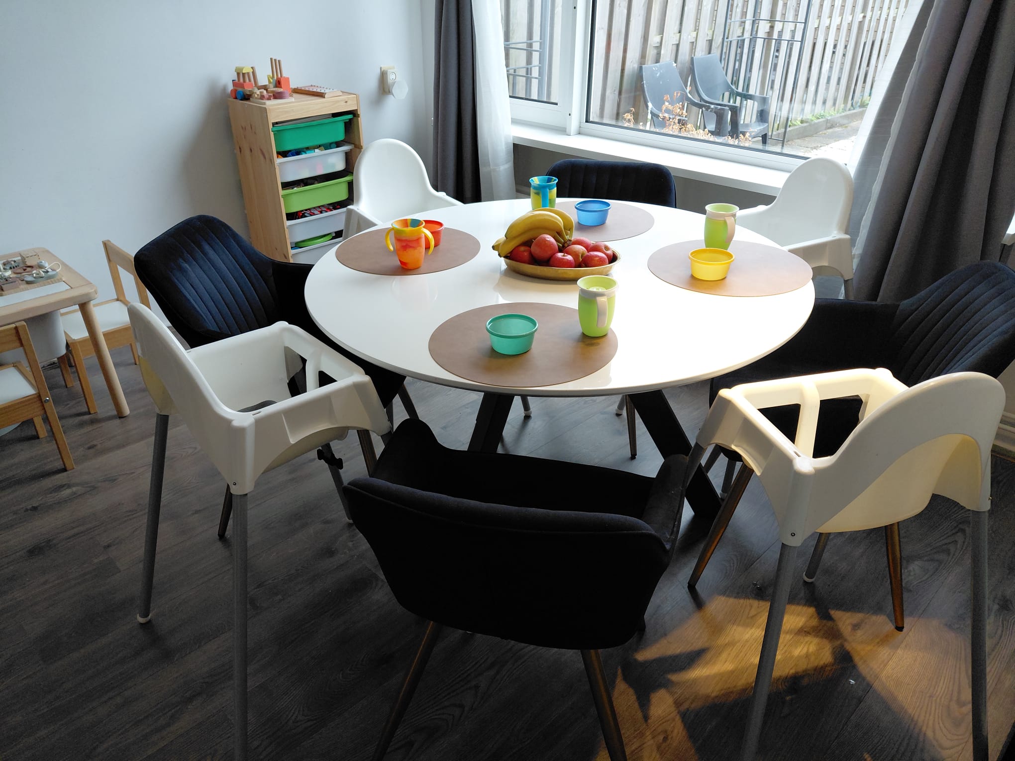 Gedekte ronde tafel met fruit, bekers en kinderstoelen