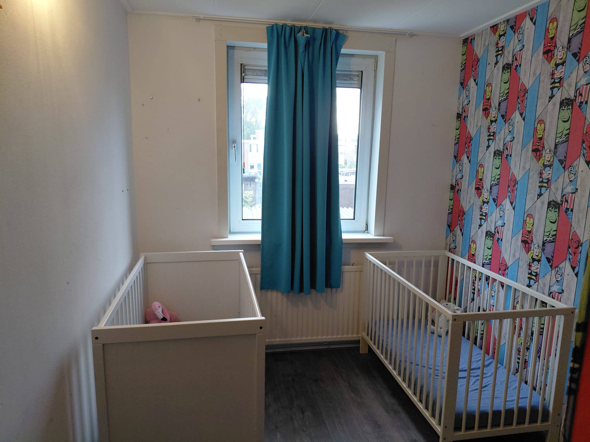 Slaapkamer met twee kinderbedjes en blauwe gordijnen