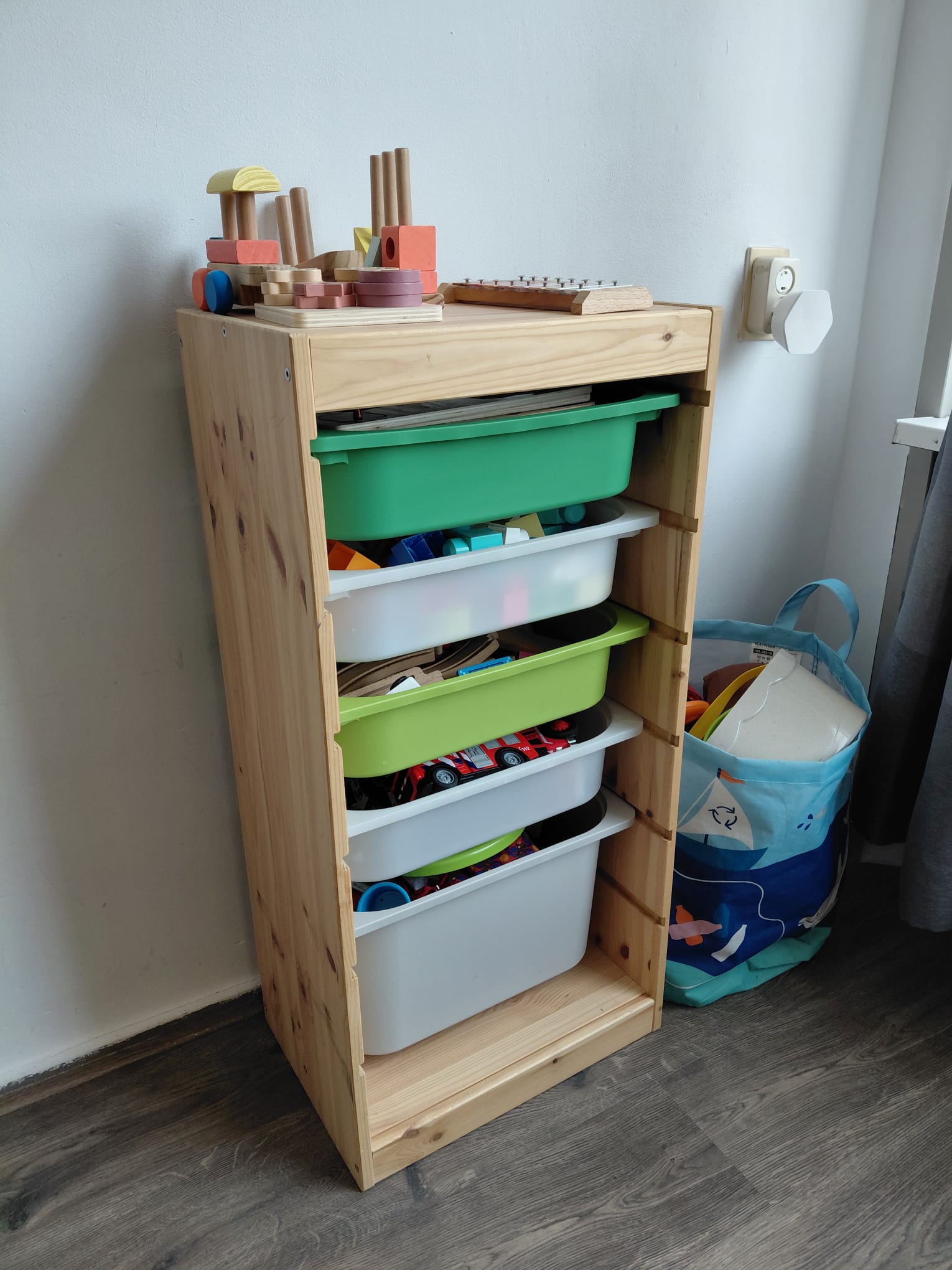 Open houten speelgoedkast met gekleurde opbergbakken